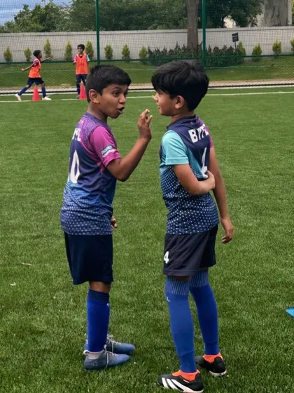 Communication is a skill we build on and off the ball. Two young teammates have a quick chat during a break in training, showcasing the friendships that form at our academy.