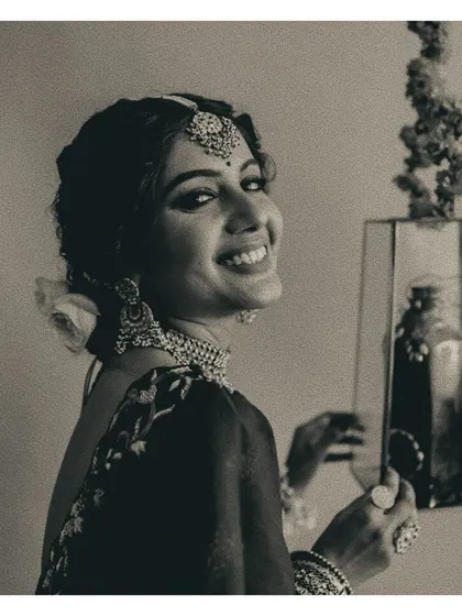 The joy of a bride. This candid black and white photo captures a beautiful, happy moment, showcasing her layered necklaces and radiant smile.