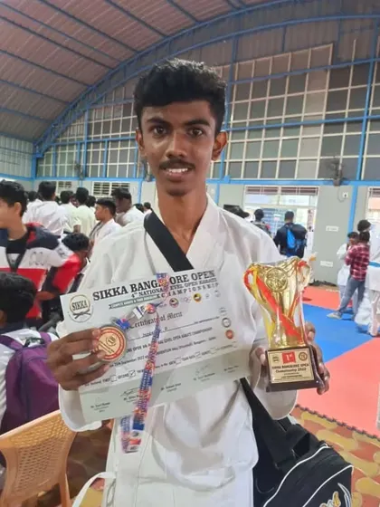 A close-up of a student with his medal and trophy, celebrating his victory at the Sikka Open.