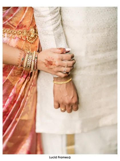 A close-up of their hands, showing the bride's henna and bangles as she holds his arm. A simple, beautiful detail.