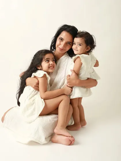 A hug full of happiness. This mother and her two daughters share a beautiful, smiling moment in their matching white dresses.