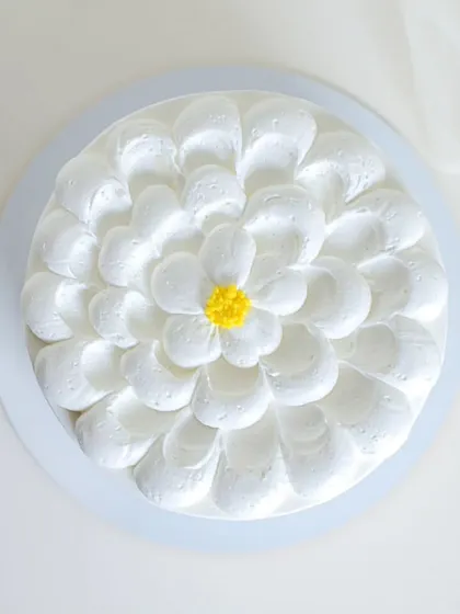 A simple and cheerful daisy cake. The petals are created with piped white chocolate ganache, making the entire cake a beautiful, edible flower.