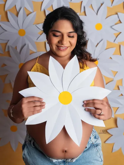 A bright and cheerful portrait with a fun daisy theme. Using simple, bold props like these paper flowers can add a playful and happy vibe to your maternity photos.