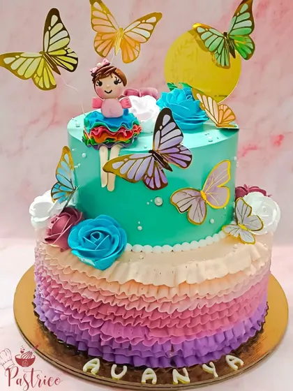 A dreamy two-tiered cake with whipped cream ruffles, a handcrafted doll, and fluttering butterflies for a first birthday.