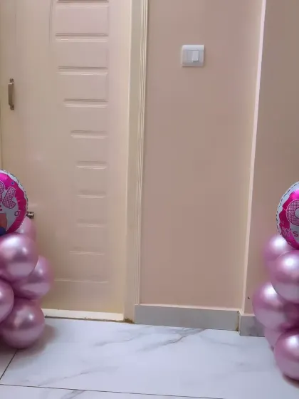 Simple and elegant balloon pillars in metallic pink stand on either side of a doorway, creating a beautiful entryway to welcome home a new baby girl.