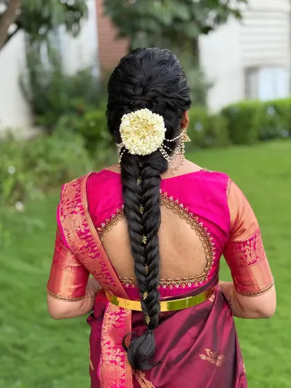 A classic fishtail braid gets a traditional touch with a large, round jasmine flower arrangement at the base. This style is perfect for brides who want a blend of modern braiding with classic floral elements.