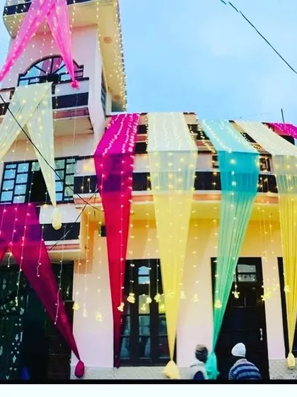 A house decorated with multi-colored drapes and fairy lights for a festive night celebration.