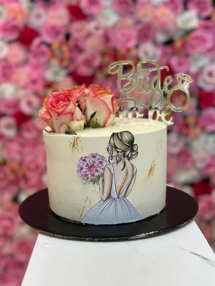 A still image of the hand-painted 'Bride to be' cake, showing the delicate artwork and the elegant combination of fresh flowers and a gold topper.