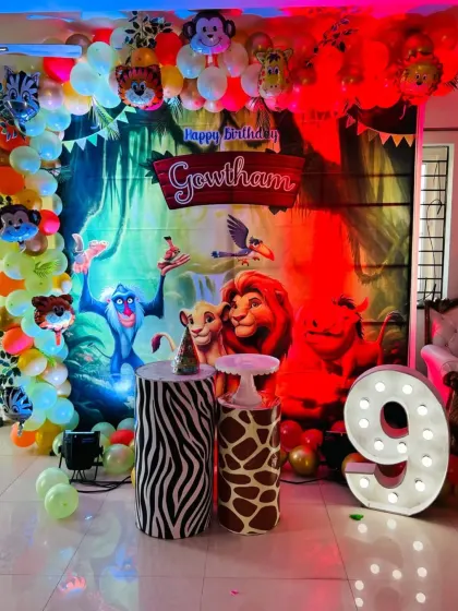 A vibrant Lion King jungle theme for Gowtham's 9th birthday, featuring a large character backdrop, animal-print pedestals, and a light-up marquee number.
