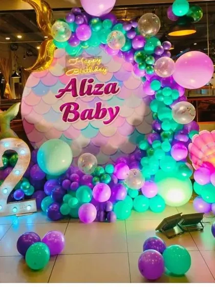 A mermaid-themed second birthday party with a custom-shaped backdrop and a '2' marquee light.