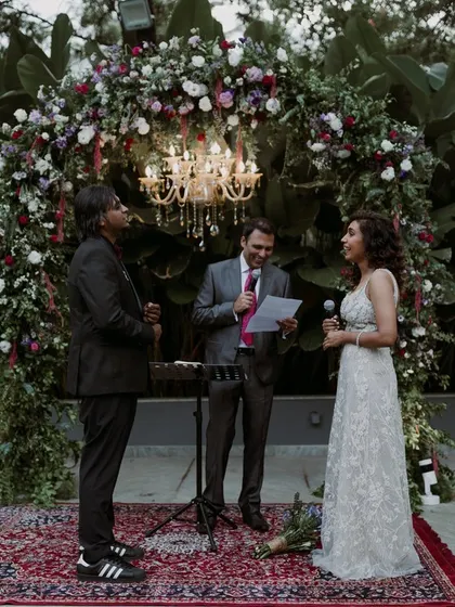 An outdoor ceremony with the couple exchanging vows under a beautiful floral arch, with lush greenery providing a stunning natural backdrop.