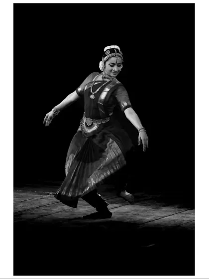 A black and white photograph capturing the timeless grace of a traditional pose. The lack of color emphasizes the form and movement.