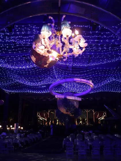 A unique chandelier installation for the celestial-themed Sangeet, where a classic crystal chandelier is encased within a planetary ring. It's these custom details that make our designs stand out.