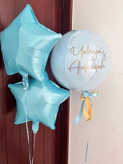 A closer look at the personalized balloon bunch for Yahya's Aqeeqah. It includes a custom bubble balloon and two light blue star shaped foil balloons.