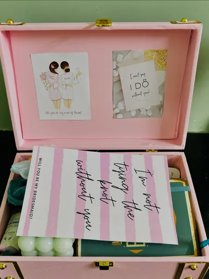 The moment of reveal for a bridesmaid proposal. The card inside the trunk reads, "I'm not tying the knot without you," a heartfelt message for a dear friend.