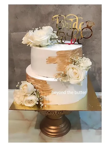 This elegant two tier "Bride to be" cake in white and gold is perfect for a sophisticated bridal shower. I used a brushed gold effect and arranged beautiful white roses to create a chic and timeless design.