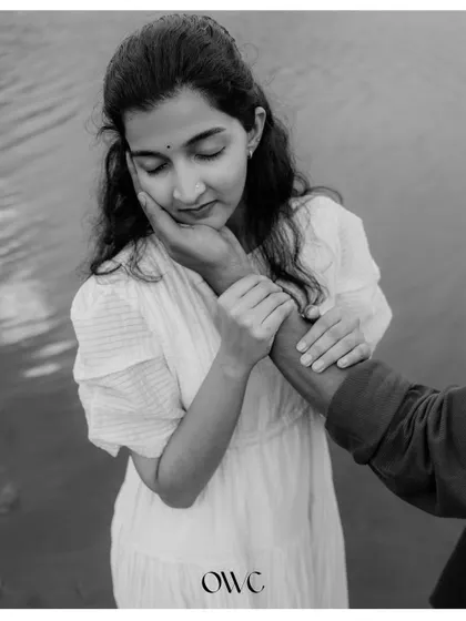 A gentle and loving black and white photo, focusing on the groom's hand caressing his partner's face.