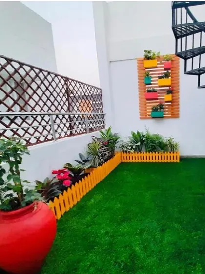 Even unconventional spaces like this terrace with a spiral staircase can become a beautiful garden. We used artificial turf, a picket fence, and a mix of planters to create a charming and playful retreat.