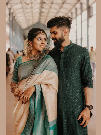 A beautiful portrait of a couple in a temple corridor, the bride holding a peacock feather.