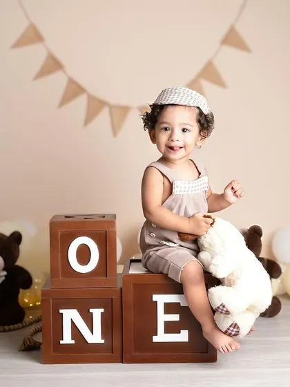 A slightly different angle of this charming, neutral-toned first birthday setup. The focus is all on his happy expression and the classic "ONE" blocks.