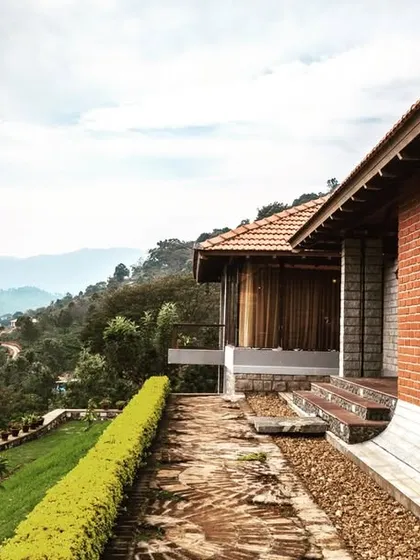 An exterior view of a brick-clad cottage in Kotagiri, overlooking the valley. The use of exposed brick and a tiled roof is a nod to colonial hill station architecture, updated with a modern sensibility.