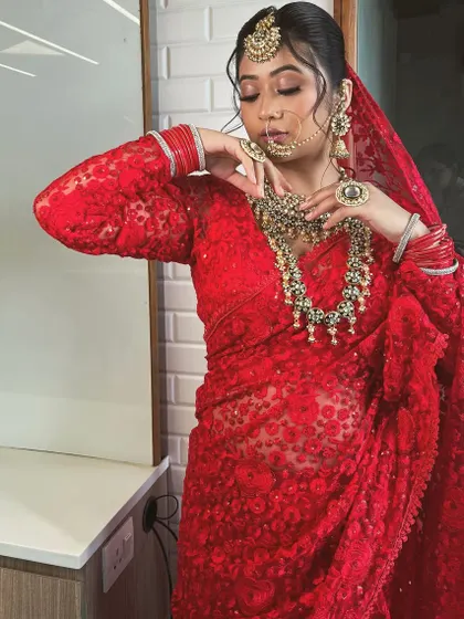 A bride styled in a stunning, sheer red embroidered saree for a traditional yet modern look.