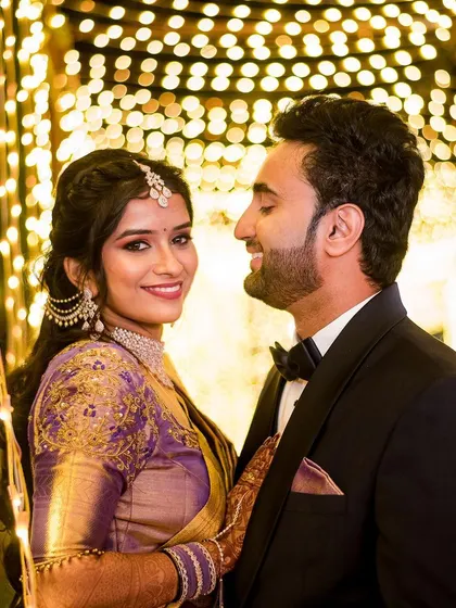 A beautiful reception portrait of the couple, with the bride looking warmly at the camera. The fairy light background adds a touch of magic.
