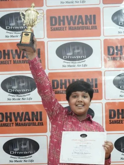 A student joyfully lifts his trophy, celebrating a successful performance.