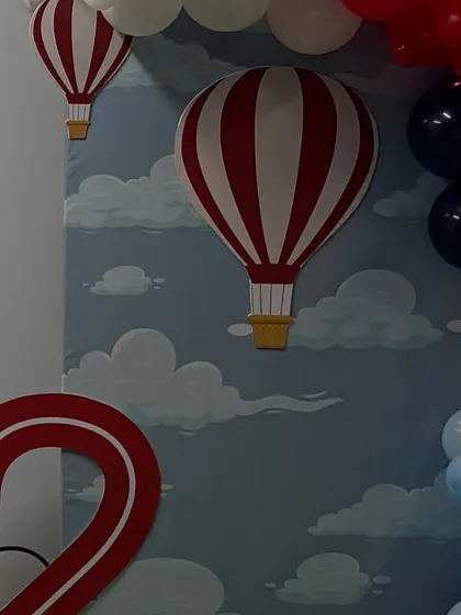 Detail of the hot air balloon cutouts on the sky-blue backdrop, adding depth and character to the airplane theme.