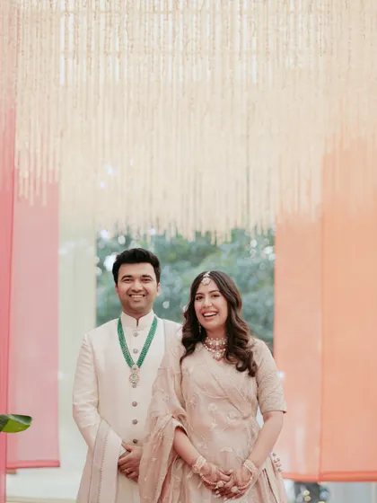 A classic portrait of the couple under a canopy of lights, smiling happily. Their coordinated outfits and the beautiful decor create a perfect frame.
