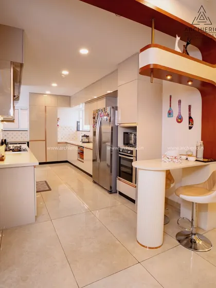 A spacious and luxurious kitchen with an extended layout, featuring a breakfast bar with a unique curved wooden element and high-gloss white cabinets.