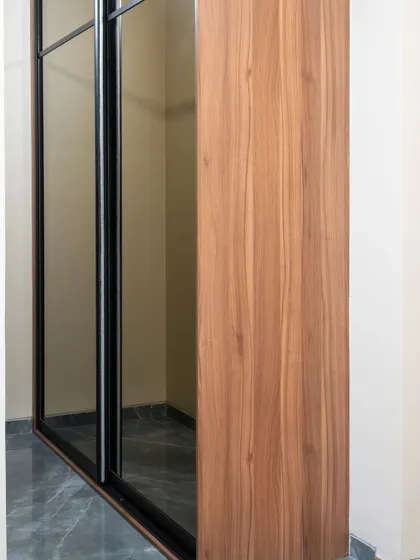 A sleek sliding wardrobe with alternating wood-finish and tinted mirror panels. This design is great for small rooms as the mirror creates an illusion of space.