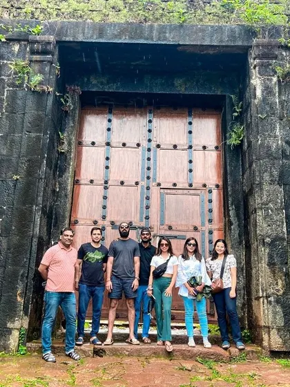 A team stands before the ancient, imposing doors of a fort along the Kodachadri trek route, blending adventure with a touch of historical exploration.