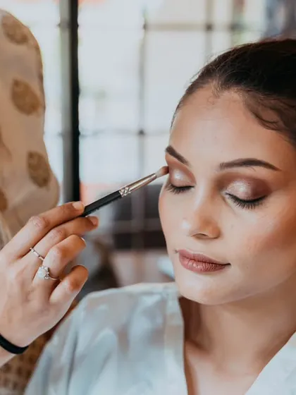 A makeup artist applying eyeshadow, showcasing the detail and care that goes into the bridal look.