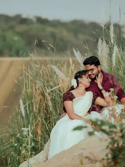 A serene pre-wedding moment by the water. The soft light and natural reeds create a peaceful and romantic atmosphere for this couple's portrait.