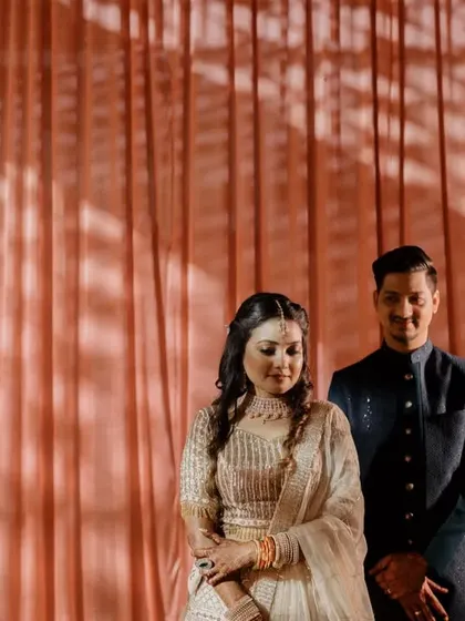 A classic couple's portrait against a simple curtain backdrop. The soft lighting and their gentle expressions create a clean, elegant, and timeless image.