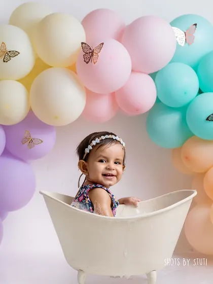 A happy baby in a tub is one of the cutest sights. The pastel butterfly-themed balloons in the background tie the whole session together, from the smash to the splash.