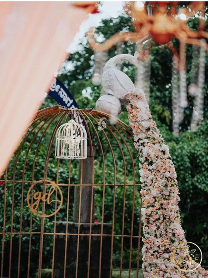 An elegant decor piece featuring a peacock with a tail of cascading flowers, placed on a golden birdcage.