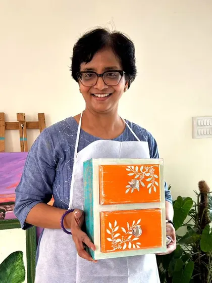 A proud participant with her finished piece, a two-drawer chest with a lovely orange and blue distressed effect.