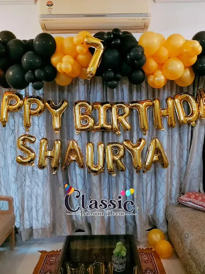 A simple yet bold balloon garland in black and orange with foil letters, perfect for a 7th birthday celebration at home.