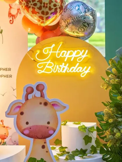 A close-up of our jungle decor, featuring a friendly giraffe, a neon 'Happy Birthday' sign, and lush greenery to complete the look.