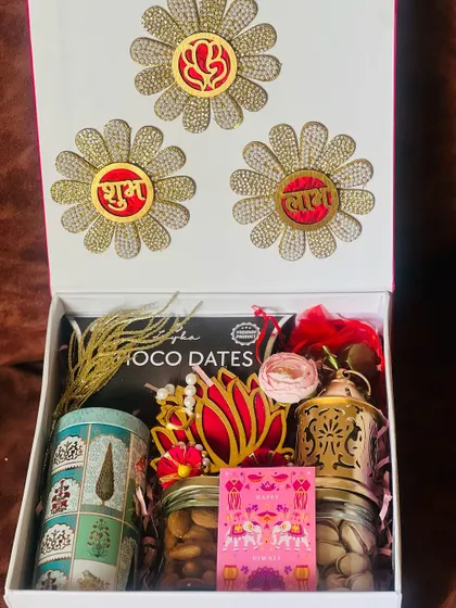 Celebrating the festival of lights with a touch of elegance. This corporate Diwali hamper features traditional items like a brass lantern and dry fruits, alongside modern touches, all presented in a beautifully decorated box.