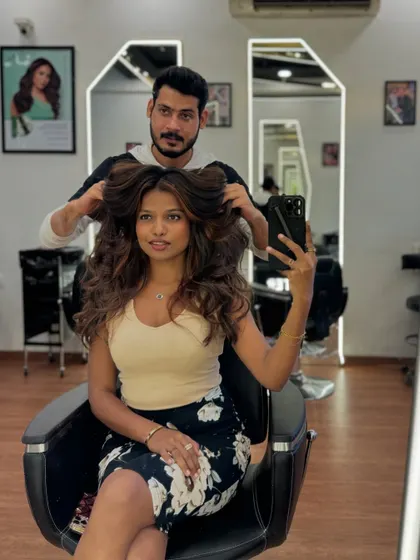 A stylist adding the finishing touches to a voluminous blowout, showcasing the client's new hair color and giving her a major confidence boost.