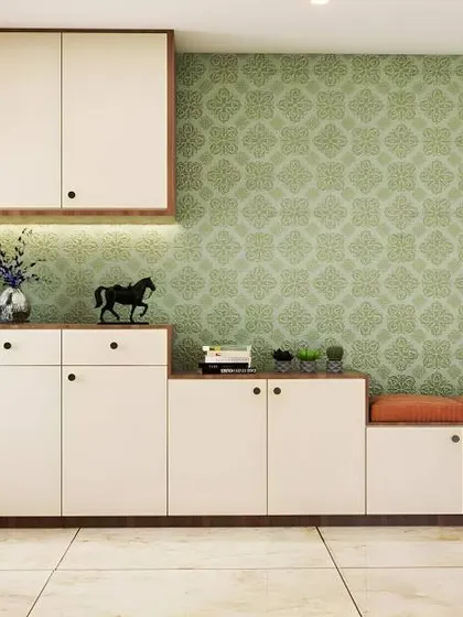 This long foyer is utilized for extensive storage, with a multi-level shoe cabinet that includes a bench and overhead cupboards. The green patterned wallpaper adds a fresh pop of color.