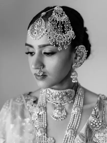 A striking black and white portrait of the bride, her elaborate jewelry and makeup creating a high-contrast, timeless image.