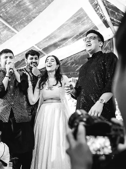 A candid black and white shot of the bride and her friends singing and celebrating, a moment of pure joy.