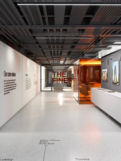 The main lobby corridor showcases the company's core values on the wall, integrating brand identity directly into the architecture. The design balances raw exposed ceilings with refined finishes like wood paneling and a sleek white console, creating a sophisticated yet honest atmosphere.