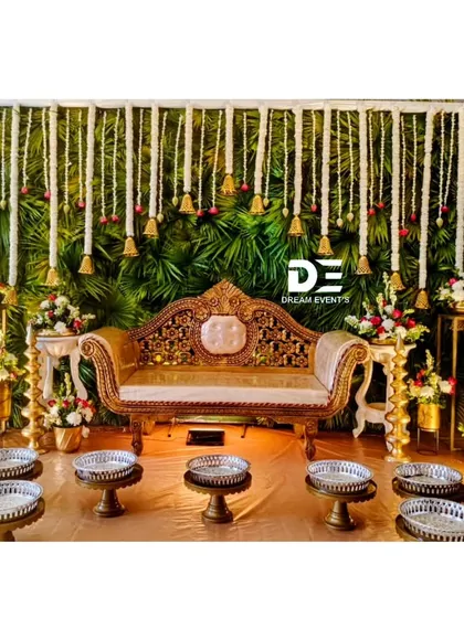 We bring the authentic spirit of a South Indian baby shower to life with this traditional setup. The backdrop features a lush wall of green leaves and hanging tuberose garlands, complemented by a royal chaise lounge and traditional seeru trays for the ceremony.