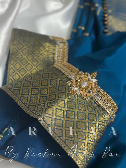 A closer look at the bell sleeve design, showing how the zari border is enhanced with a custom-made brooch-style embroidery piece.