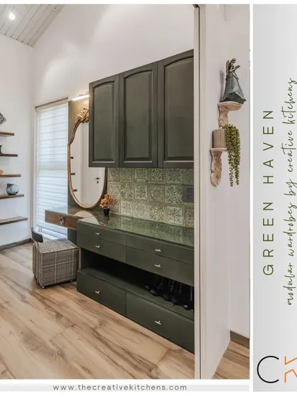A view into the "Green Haven" walk-in wardrobe. This image highlights the custom dressing area, with pine green cabinetry, a glass top, and specialized storage for shoes and accessories, all framed by a beautiful antique-style mirror.